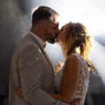 Photographe mariage : baiser des mariés en contre-jour, lumière naturelle de fin de journée